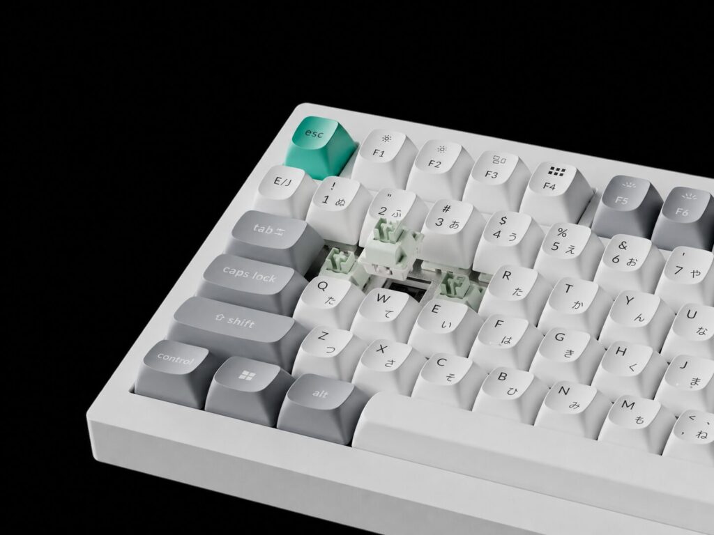 ホワイトのKeychron C75 TMR 8Kキーボードを斜めから捉えた写真。ティール色のescキーと、キーキャップを外して見えるライムグリーンの磁気スイッチ