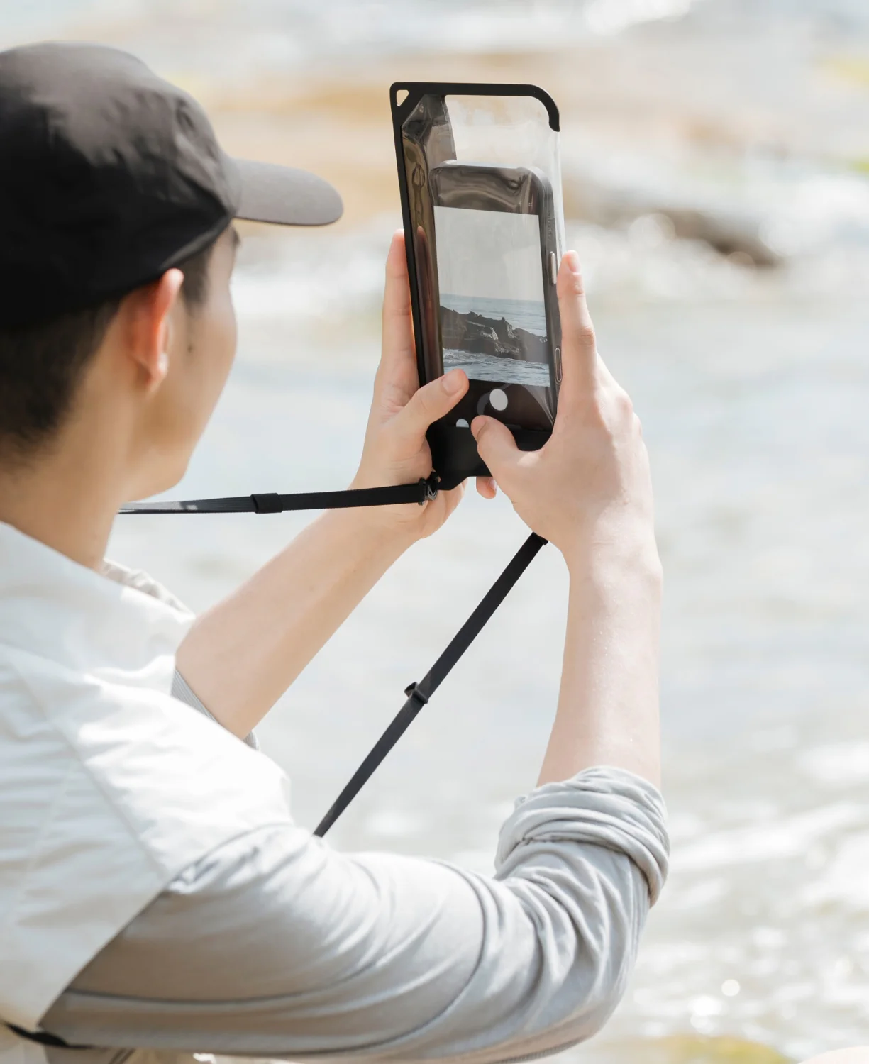 AquaSeal 2-way フォンポーチに入れたスマートフォンで水辺を撮影する男性